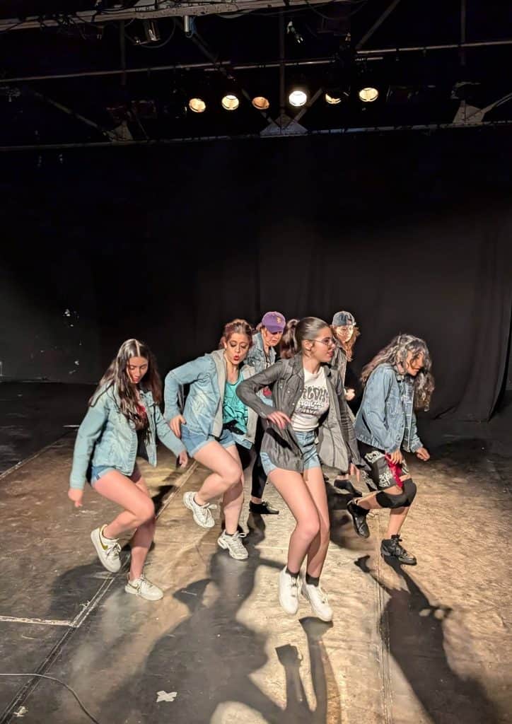 Jóvenes bailarinas en práctica de danza moderna en escenario de Delmis Dance Studio.