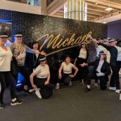 Grupo de bailarinas en evento de Michael Dance, posando con sombreros y ropa deportiva en interior. Bailarinas en grupo con sombreros y ropa deportiva, posando en evento de Michael Dance.